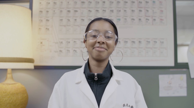 Student Smiling in front of Periodic table